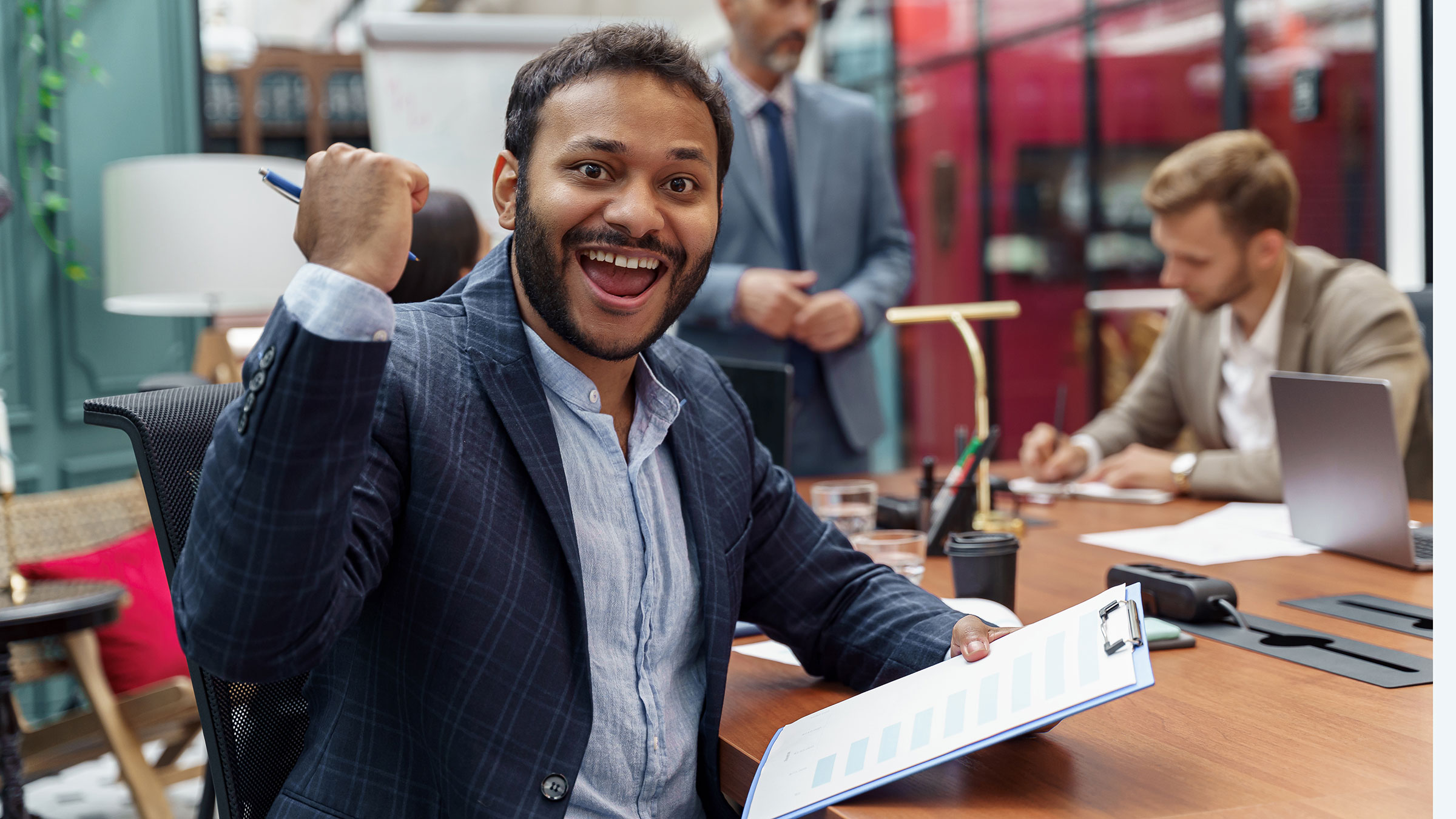 Smiling businessman sitting on meeting in modern office and looking at camera.
