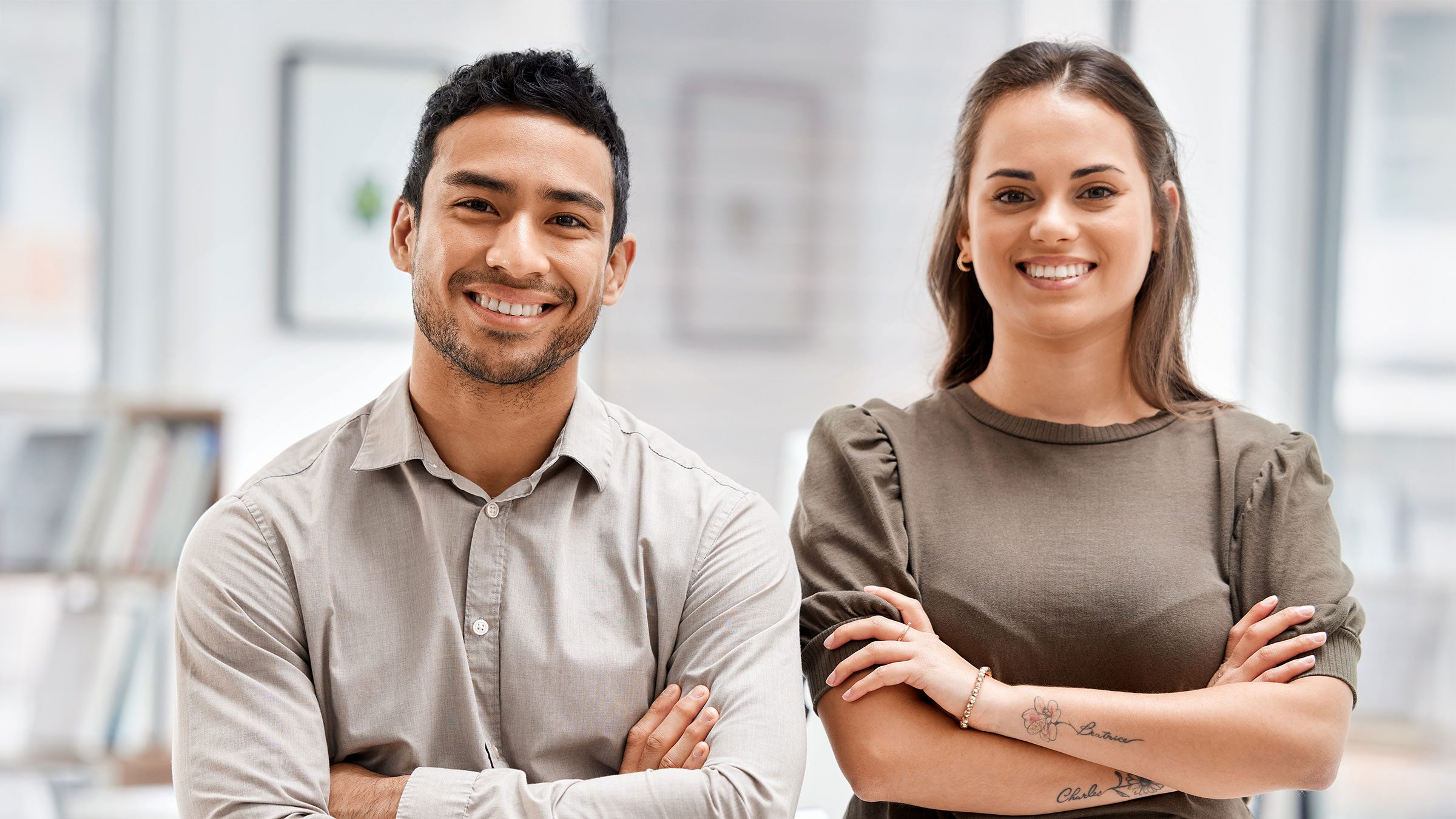 Two young business professionals with their arms folded in the office