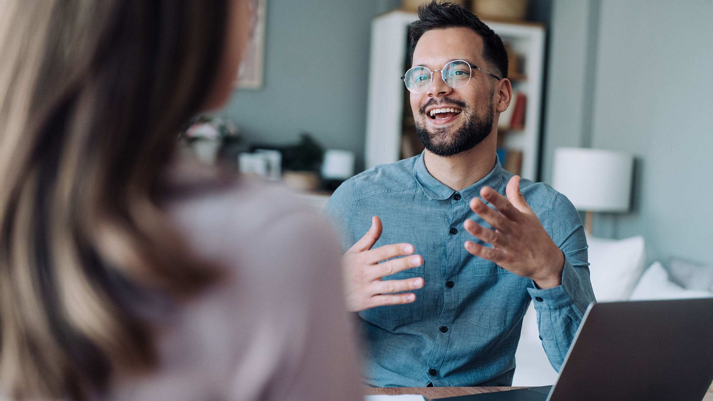 Confident man having a discussion with female colleague, smiling, making eye contact and using open body language.