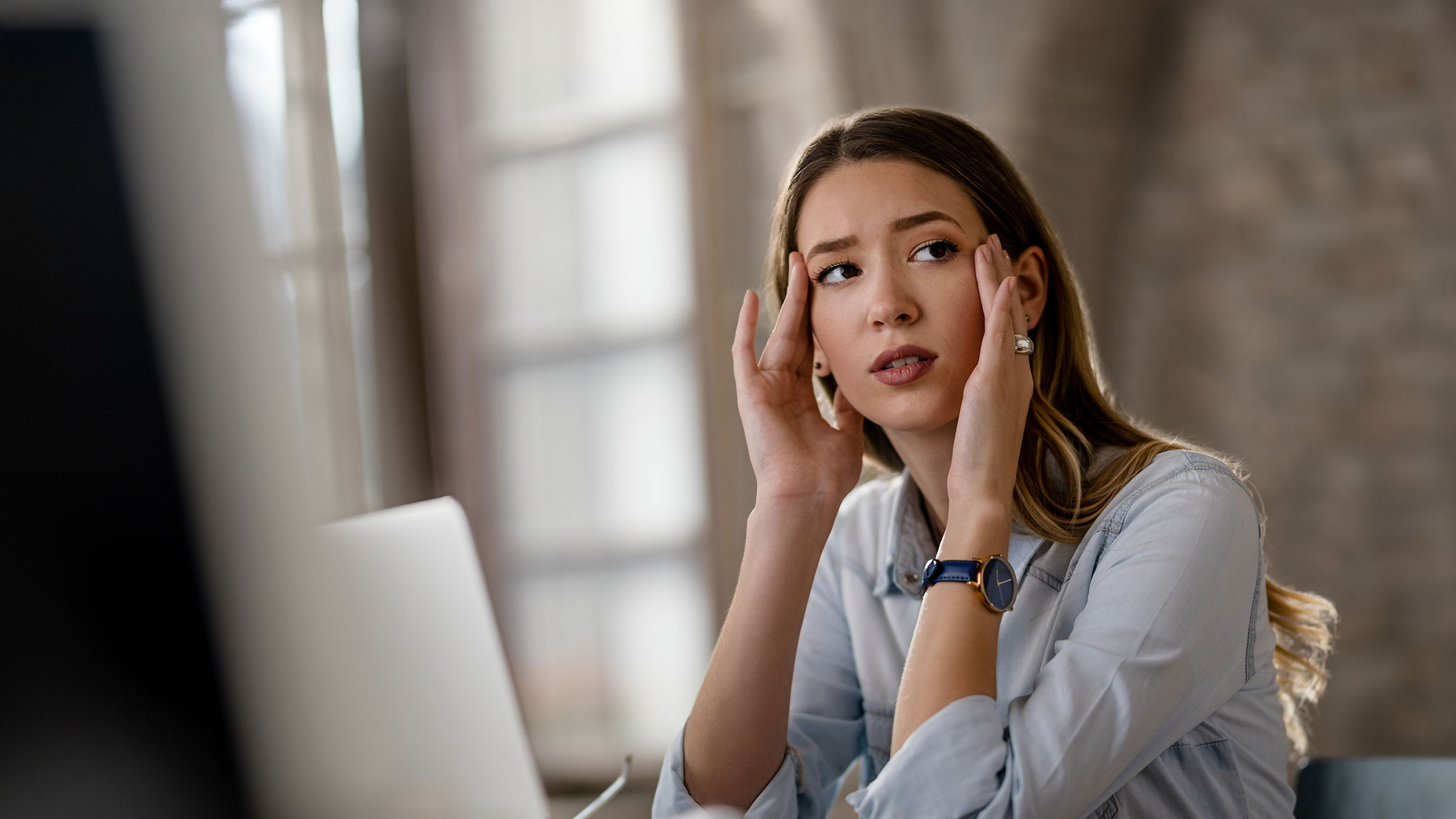 Young pensive businesswoman looking away while working in the office