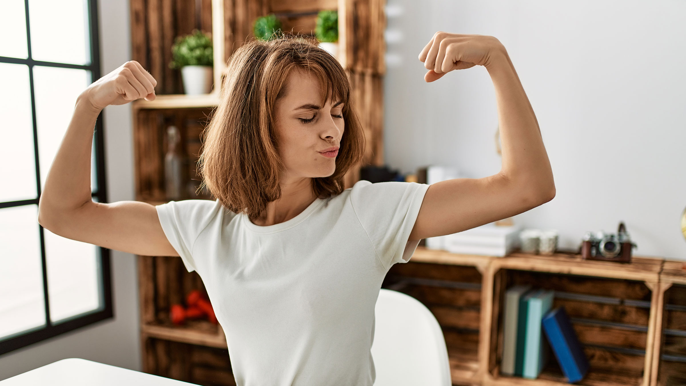 Young woman flexing muscles in both arms showing her strength