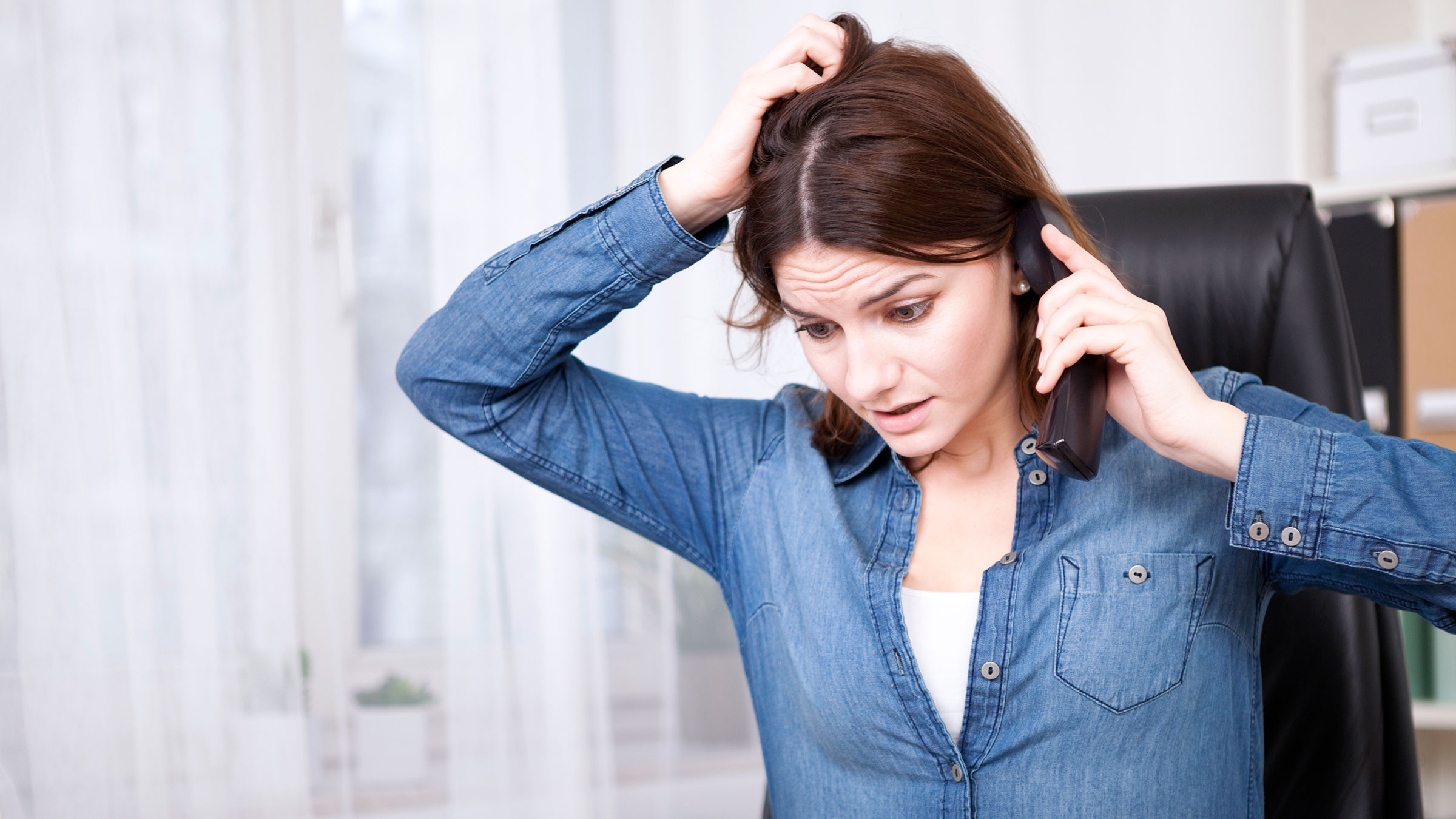 Frustrated worried woman talking on the telephone and scratching her head