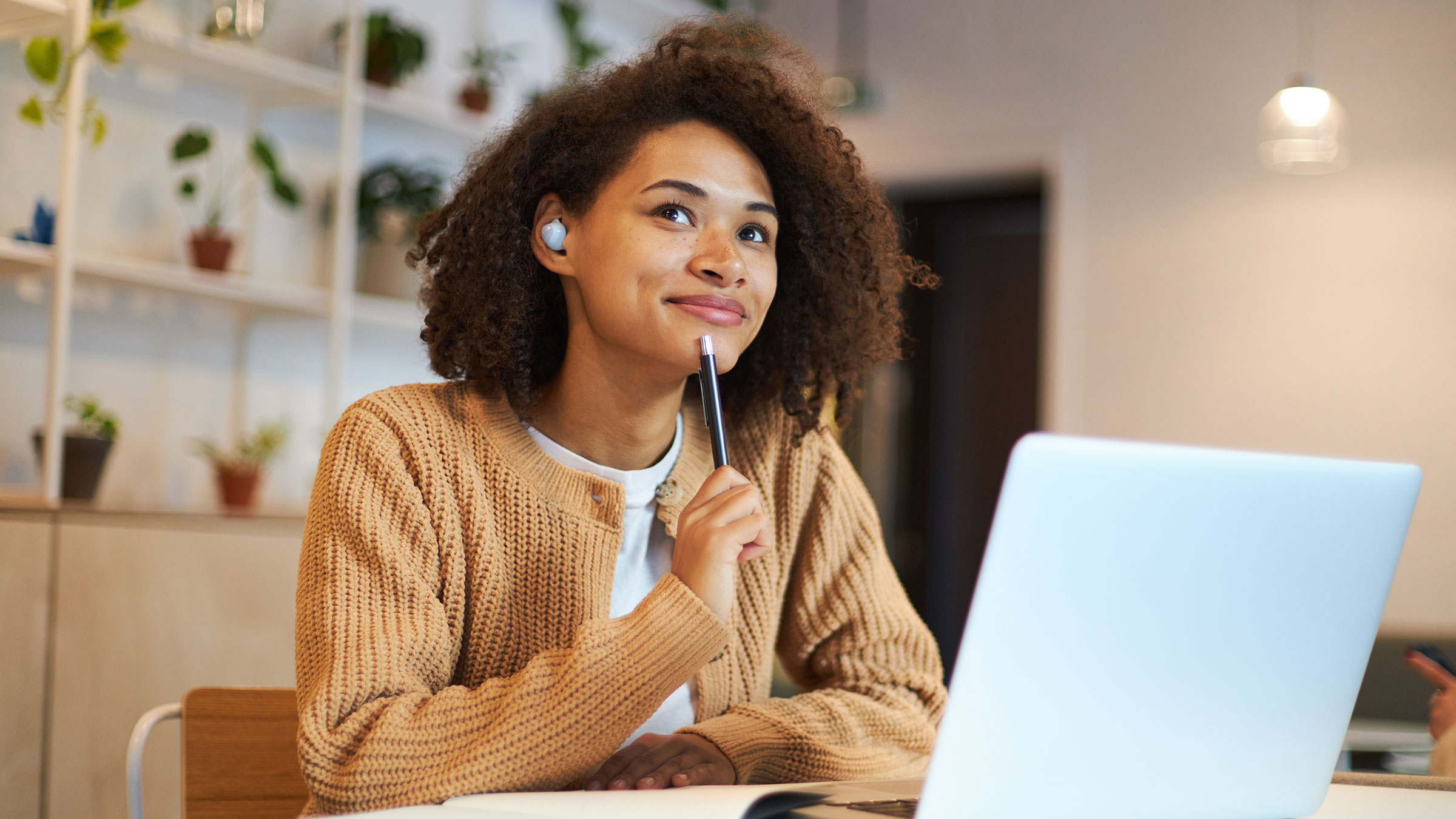 Young woman in front of laptop thinking and looking in the distance