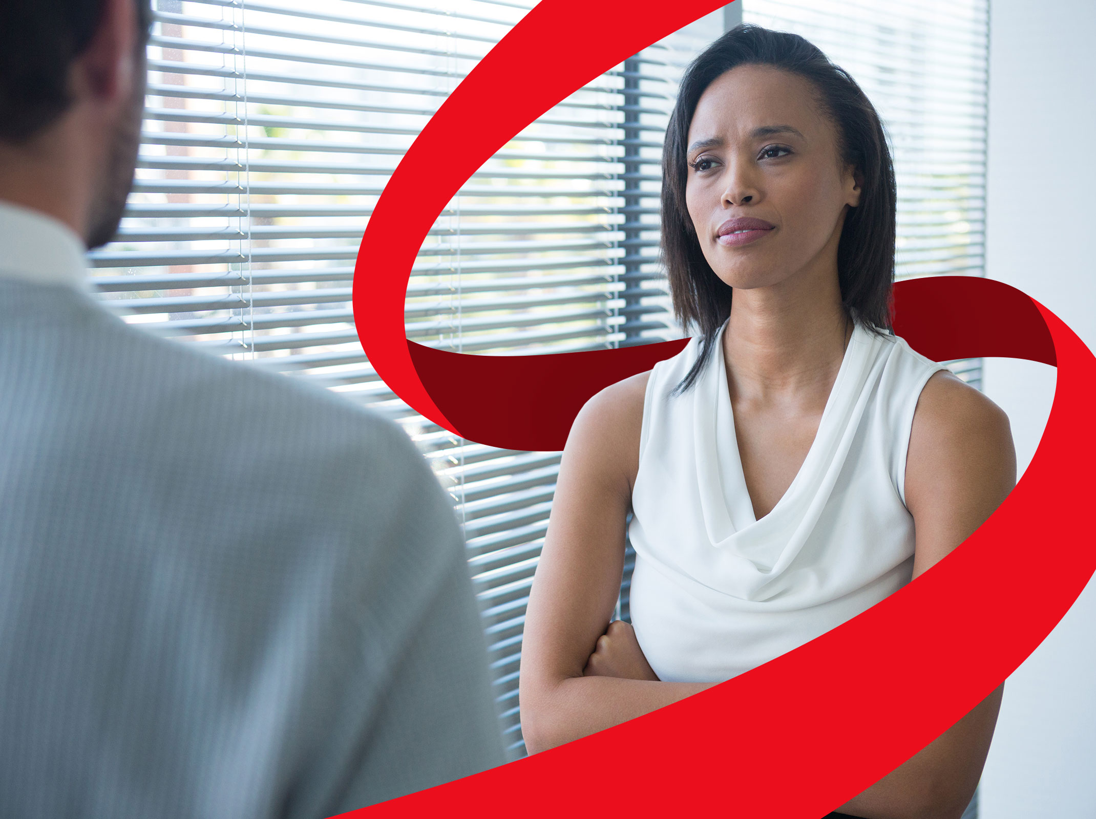 A female business professional looking uncomfortable as she has a conversation with another business professional. They are in an office setting.