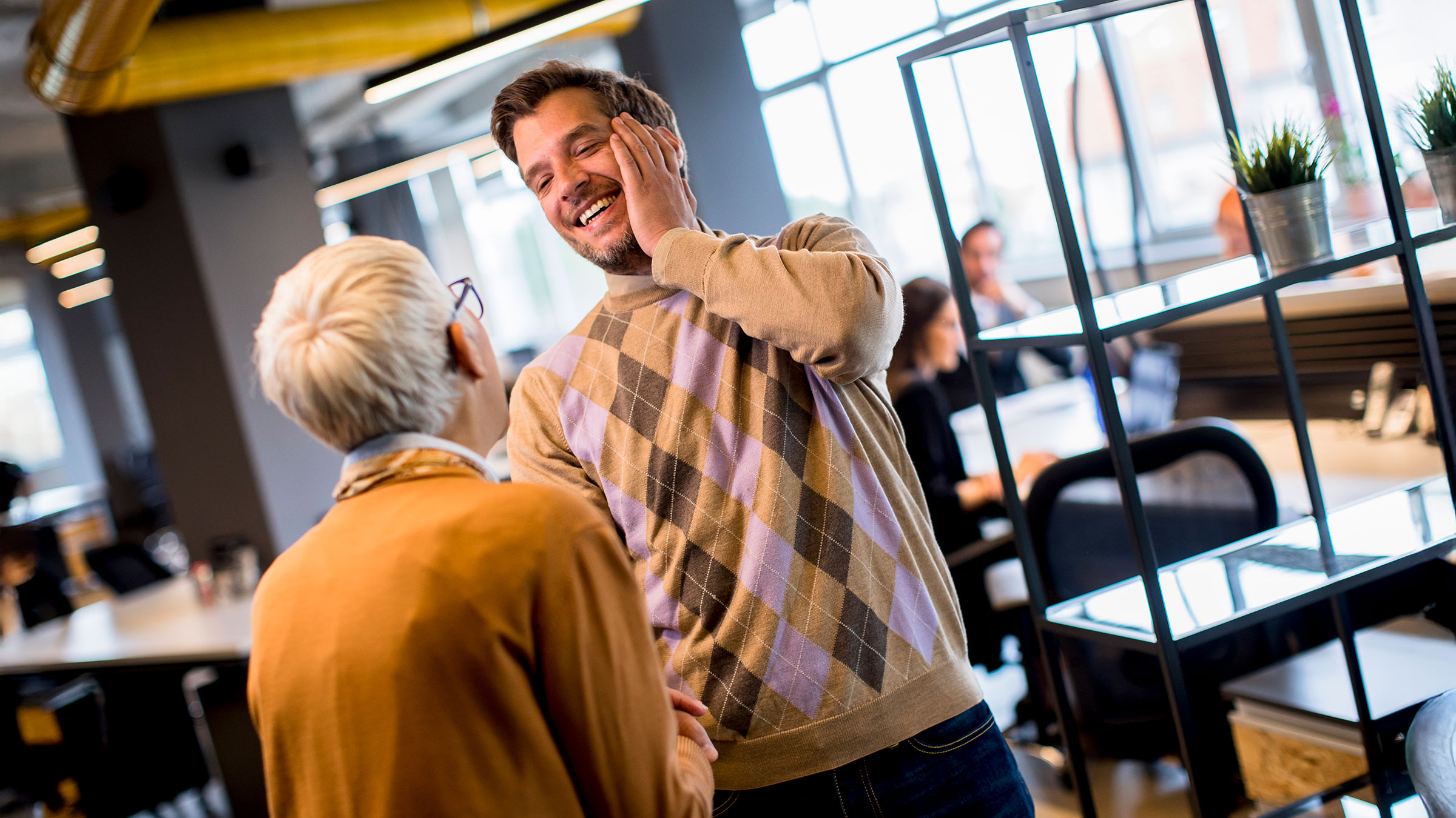 Senior business woman showing sincere appreciation to young business man in the office