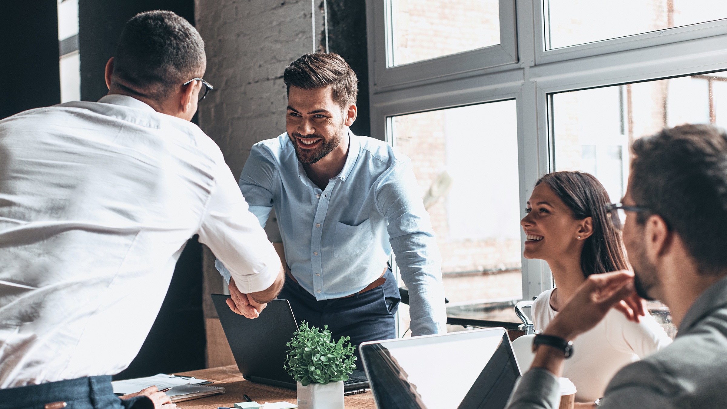 two men shaking hands across a table in a business meeting
