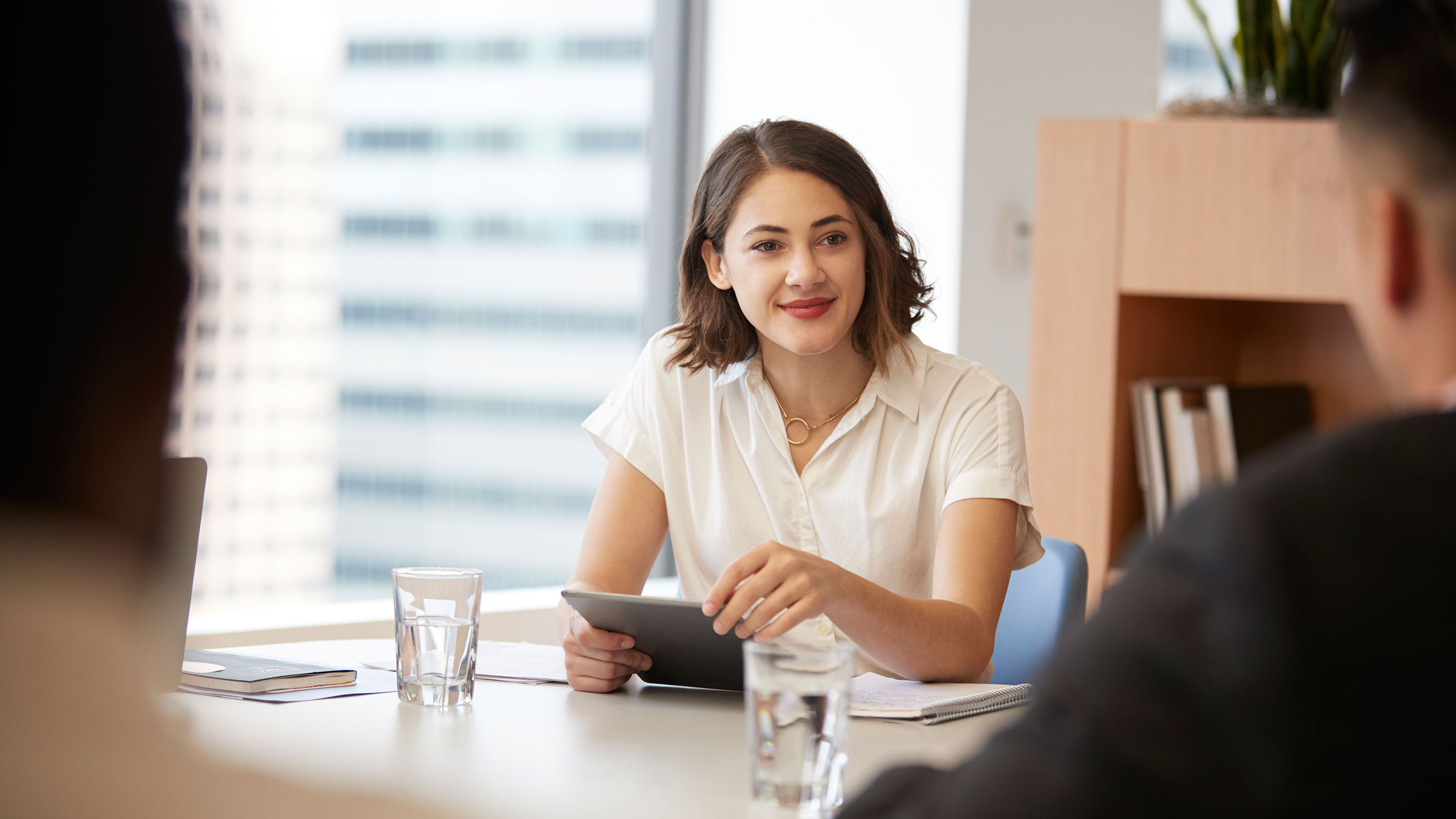 Businesswoman with digital tablet sitting at table meeting with colleagues