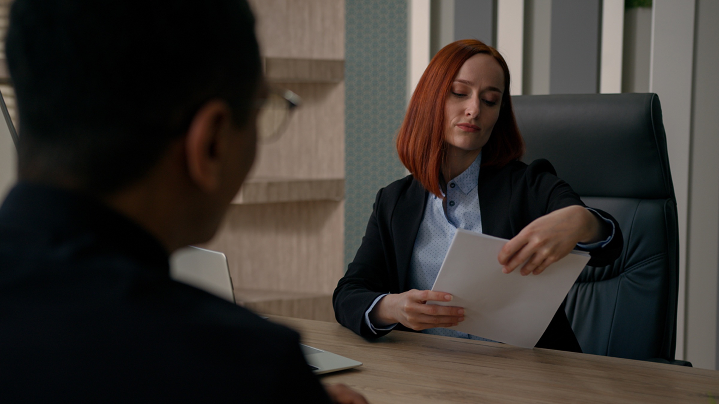 Female hiring manager looking dubiously at man's resume during interview
