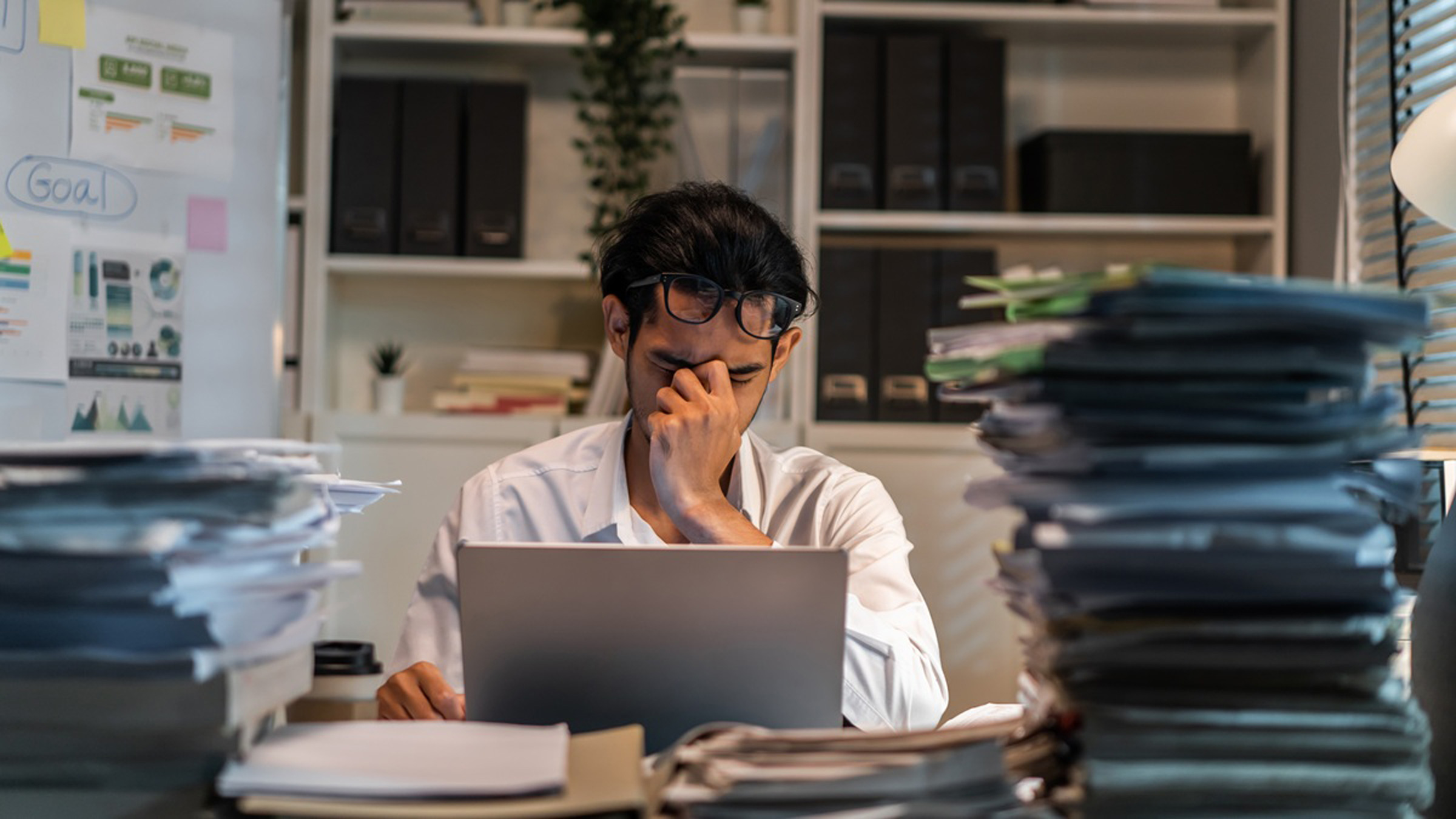 Overwhelmed worker with piles of papers on desk