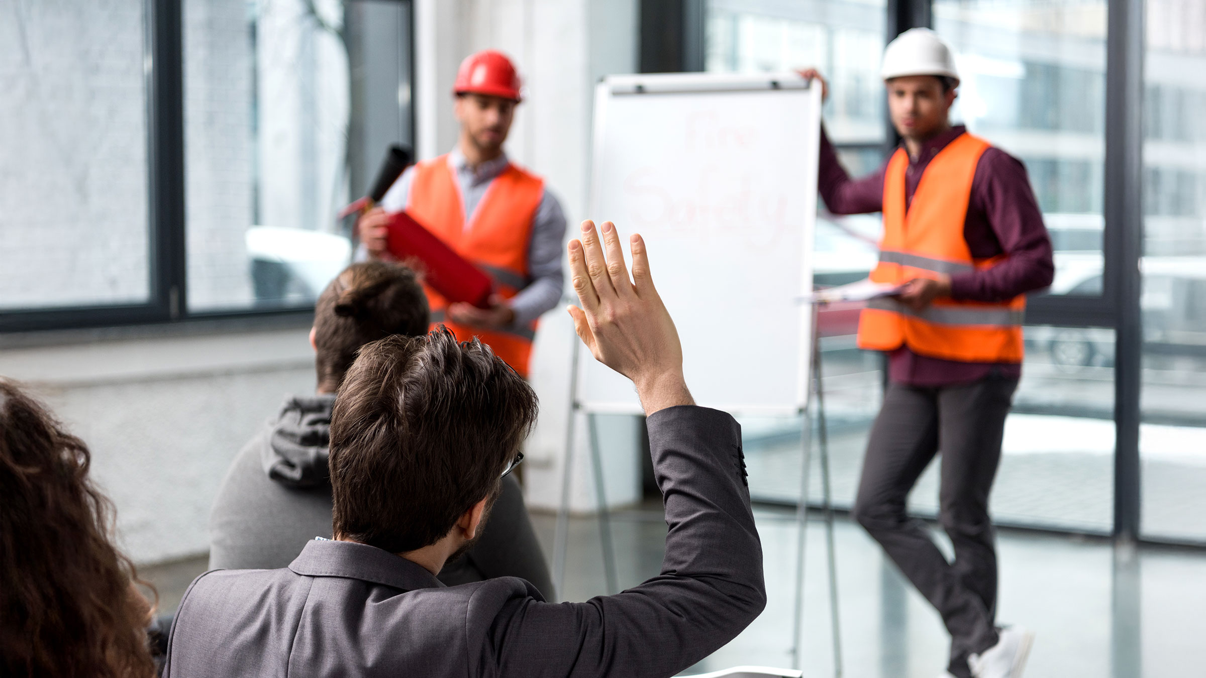 Man raising hand near firemen in fire safety training class