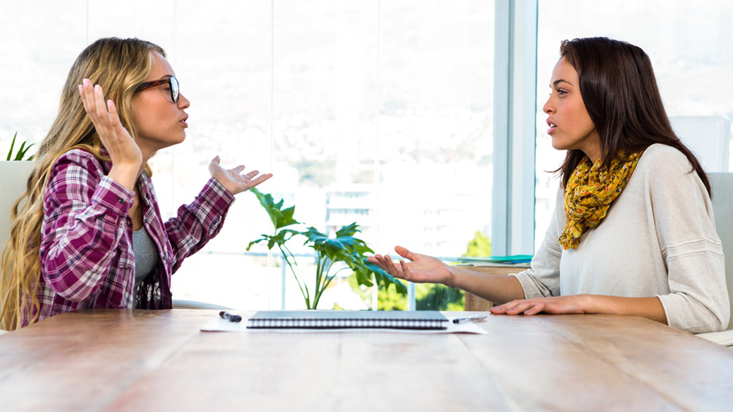 Two women in workplace conversation, one behaving defensively