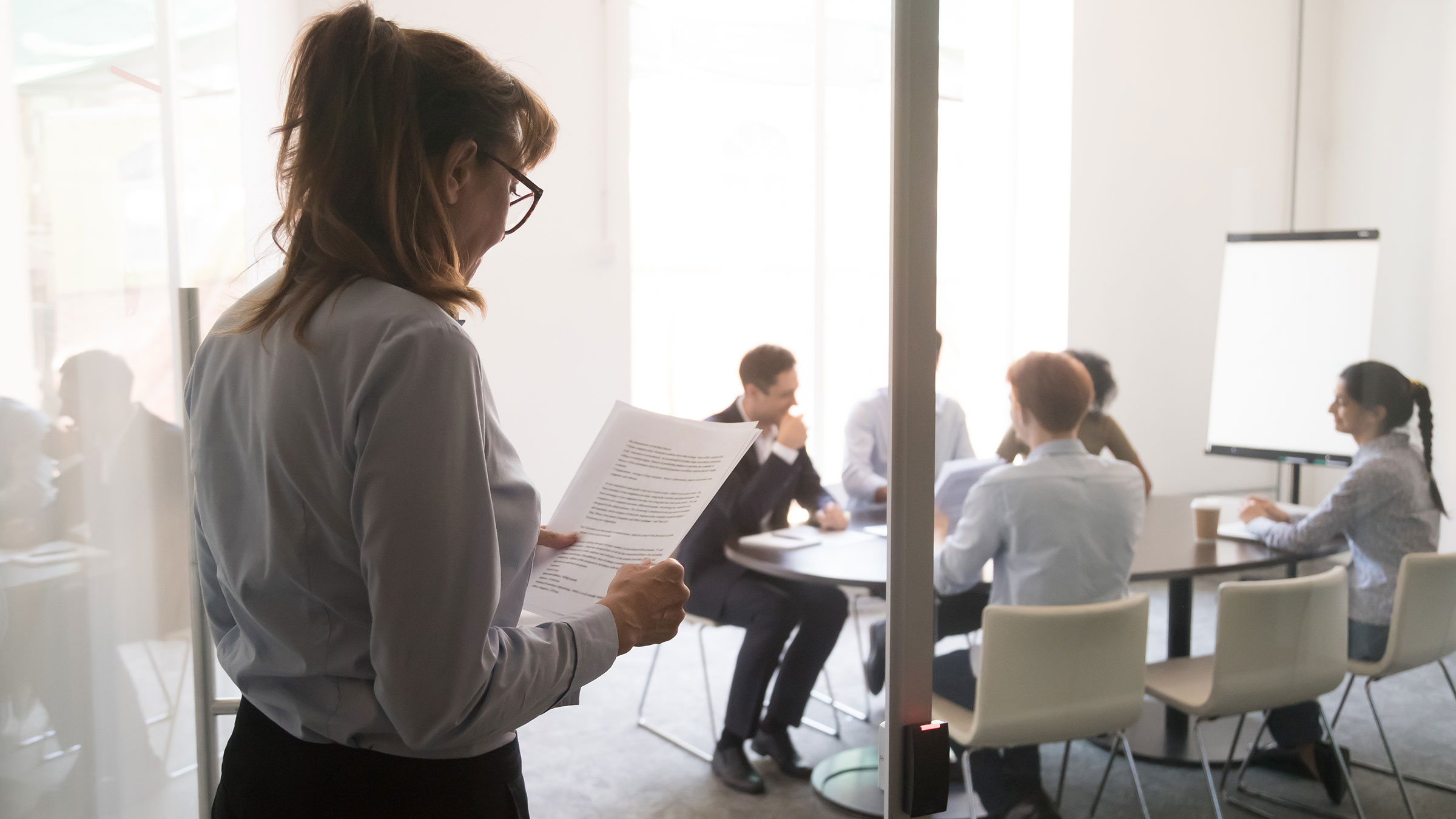 Nervous businesswoman walking into conference room holding speech in hands