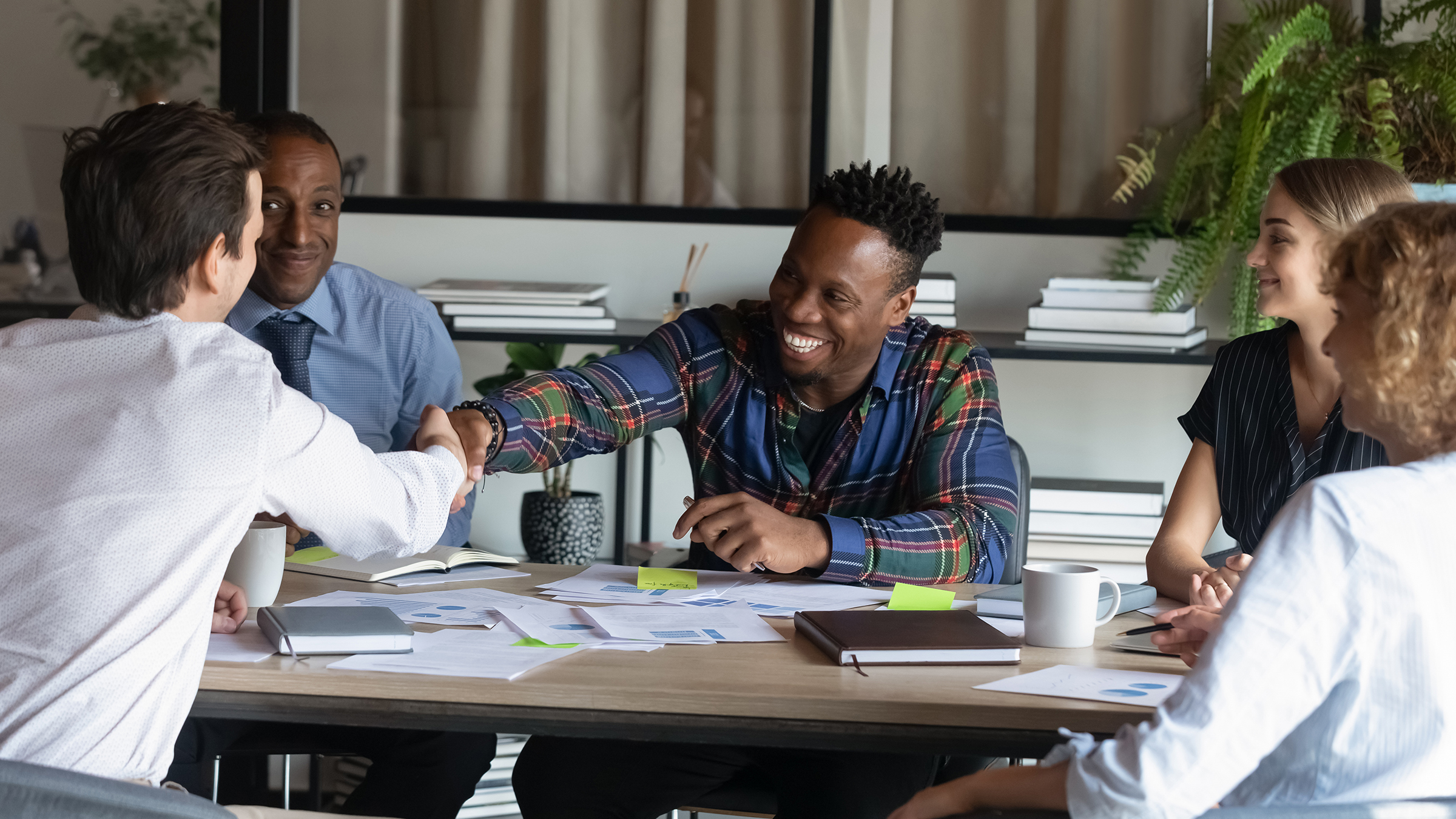 Two men shaking hands in a diverse group meeting