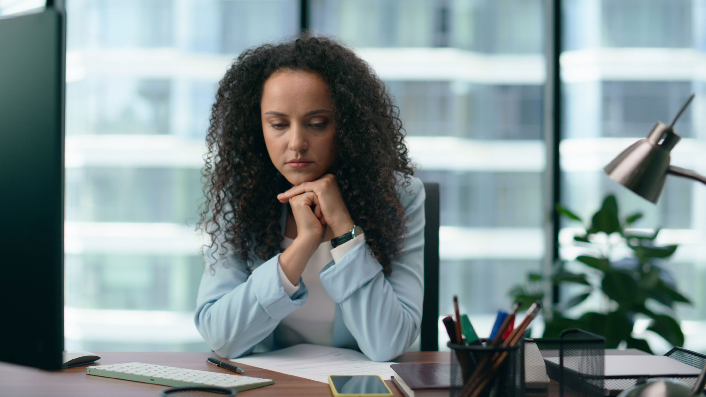 Woman sitting at desk looking tired and upset