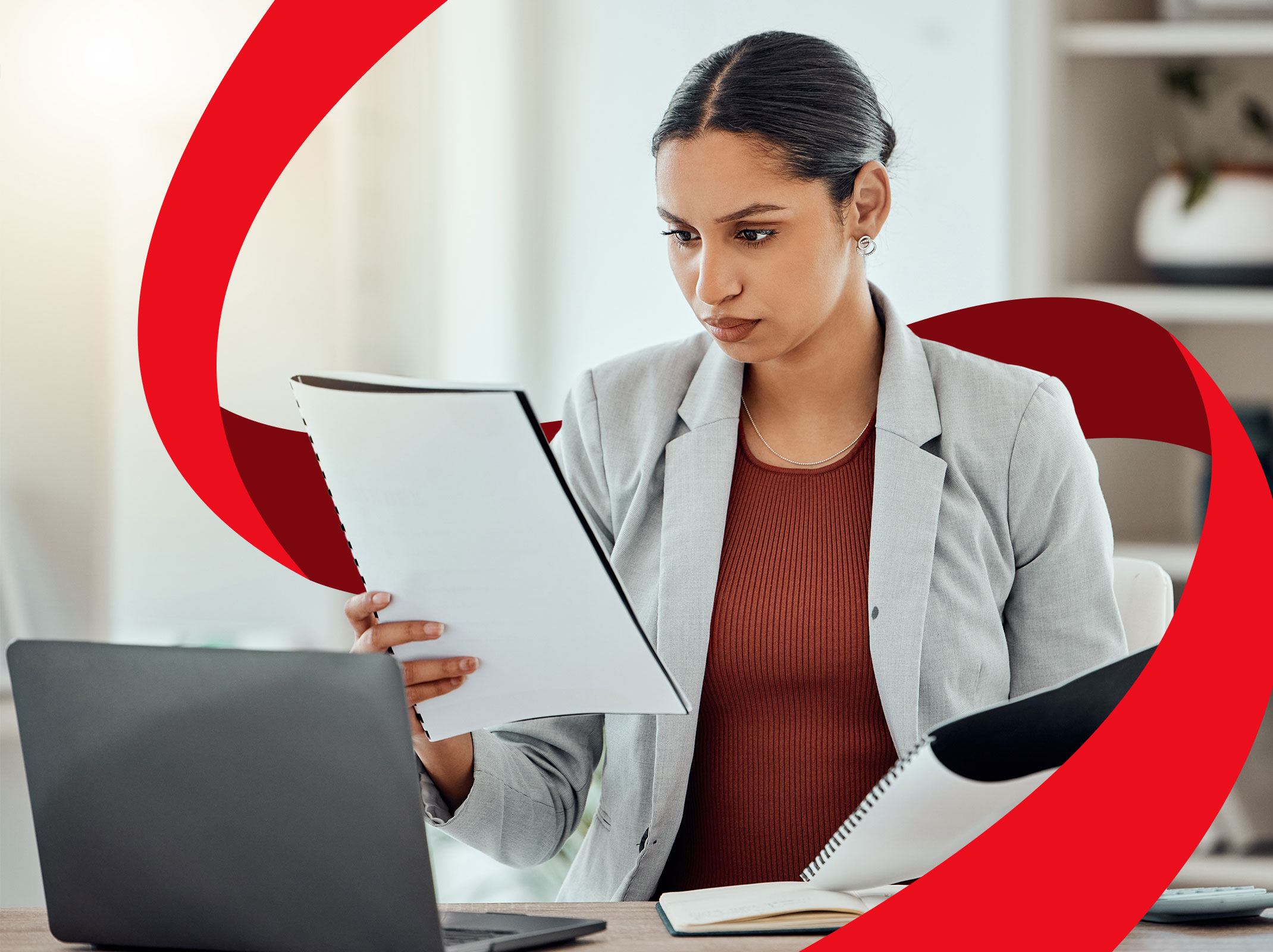 A Human Resources professional reviewing documents in front of a laptop in an office setting.