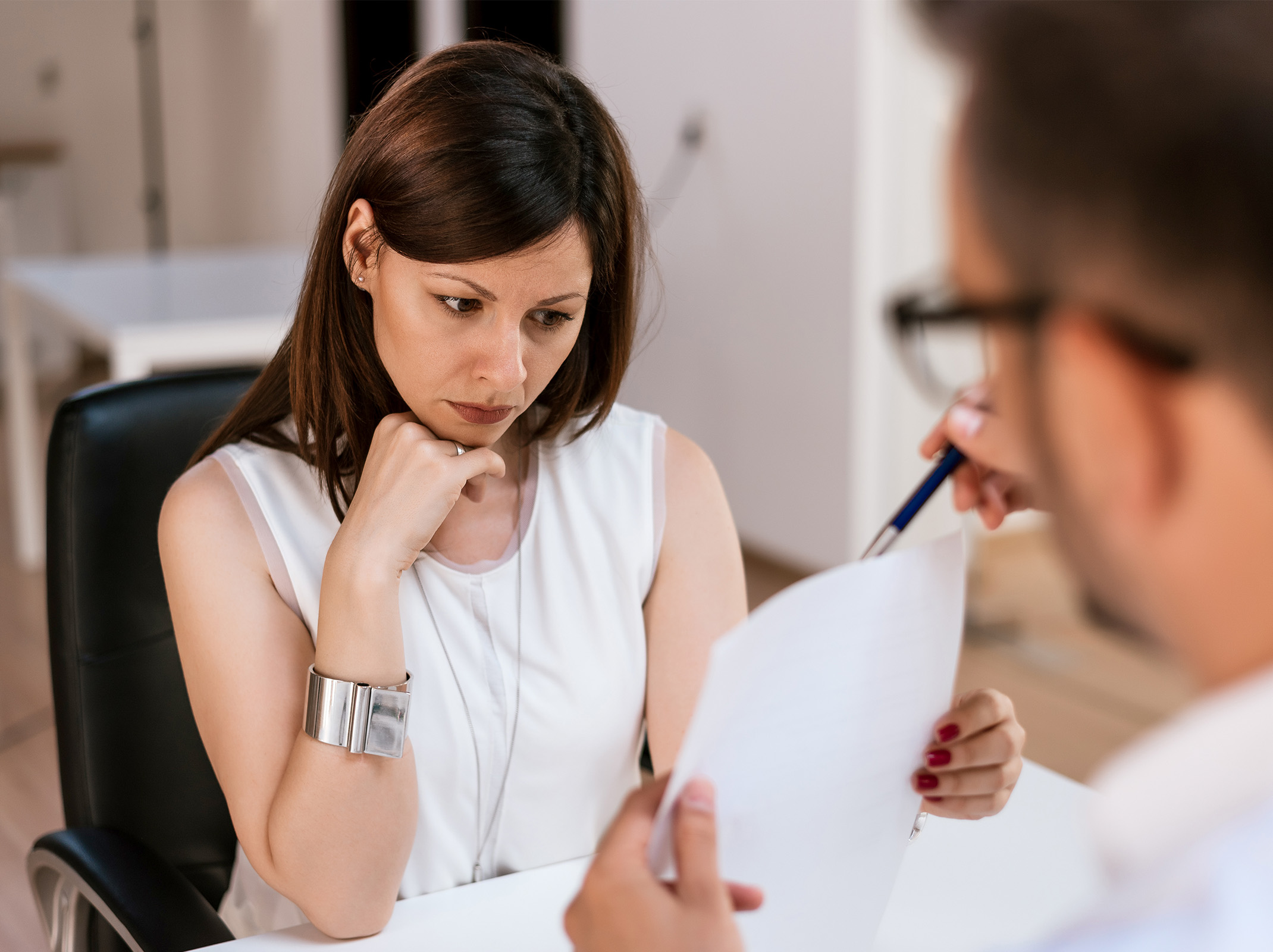 Professional reviewing document with hand on chin during meeting