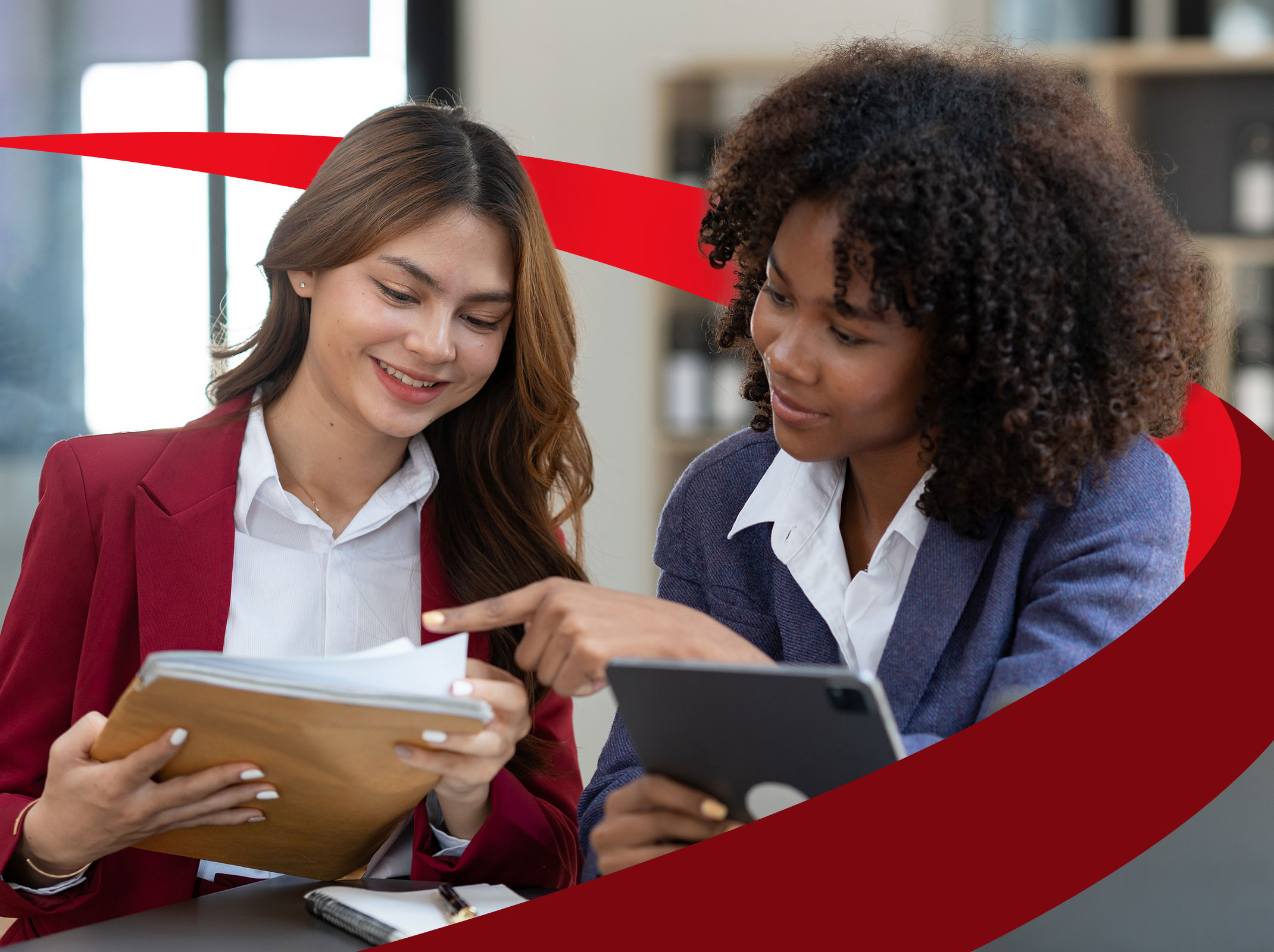 A manager providing feedback to an employee in an office setting. She is pointing a a stack of papers that the other employee is holding.