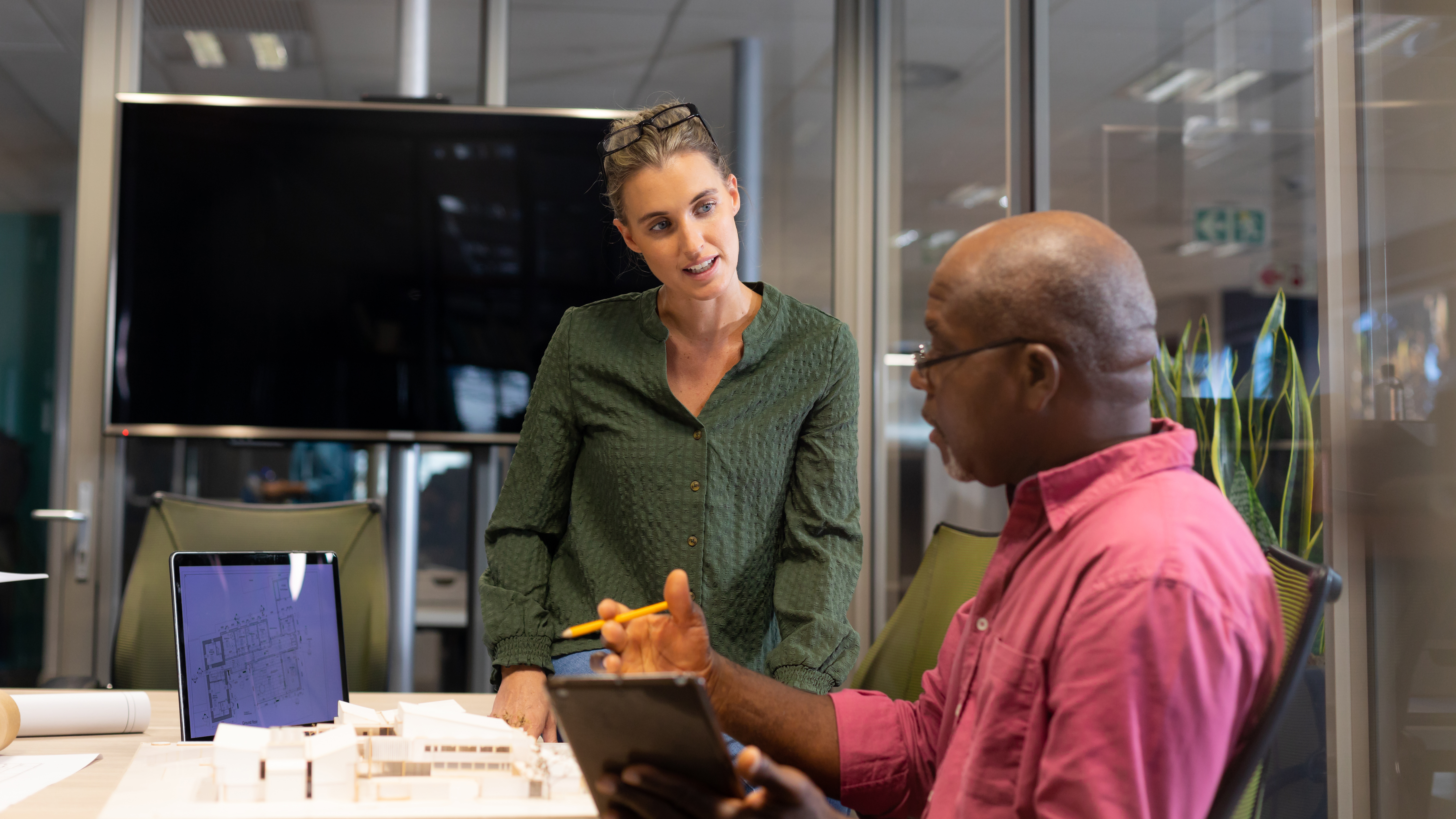 A man seated at a table explaining something to a coworker