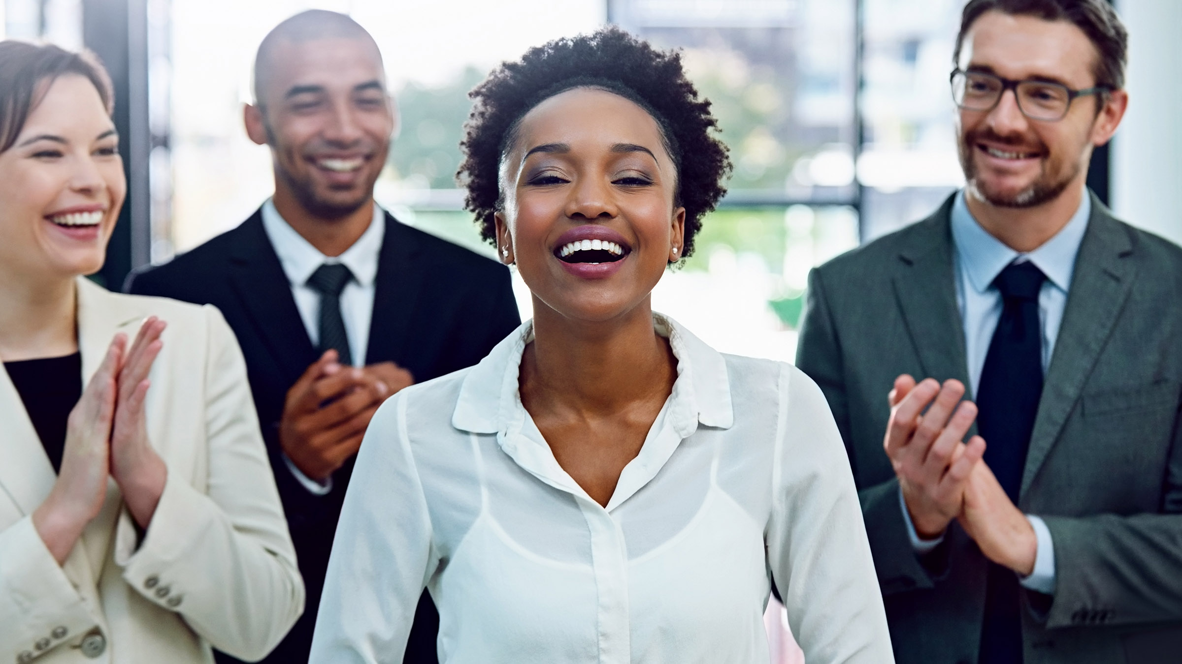 business team applauding woman at the center of the group