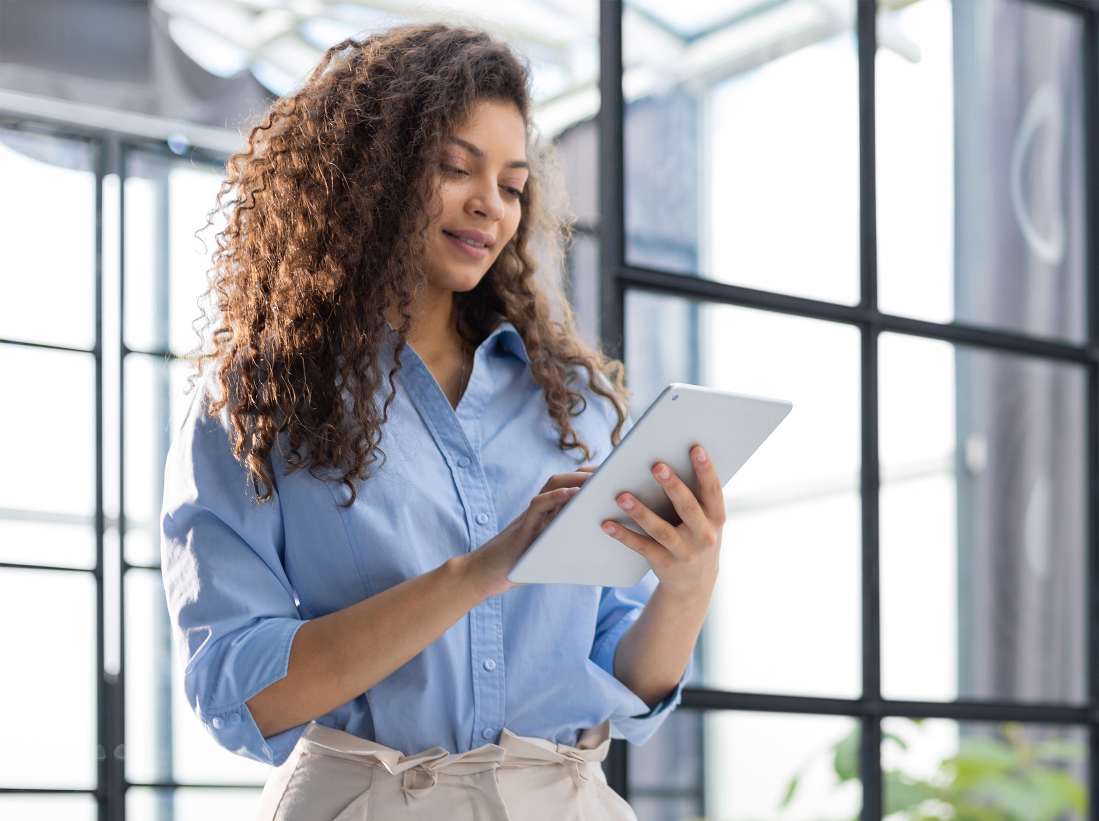 Business professional using a tablet in a modern workspace, representing everyday use of AI tools.