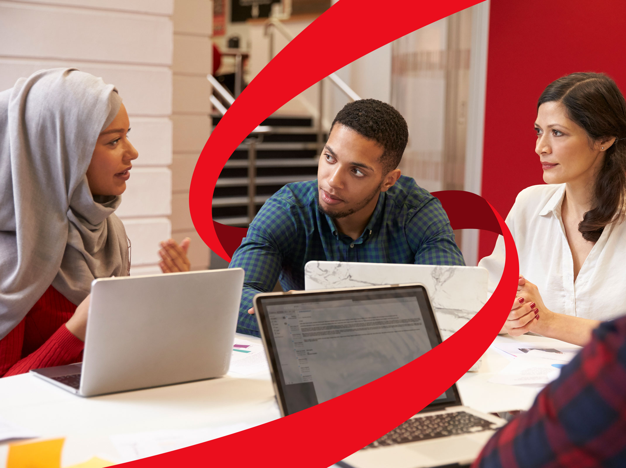 Three business professionals communicating respectful over a conference tables with laptops in front of them.