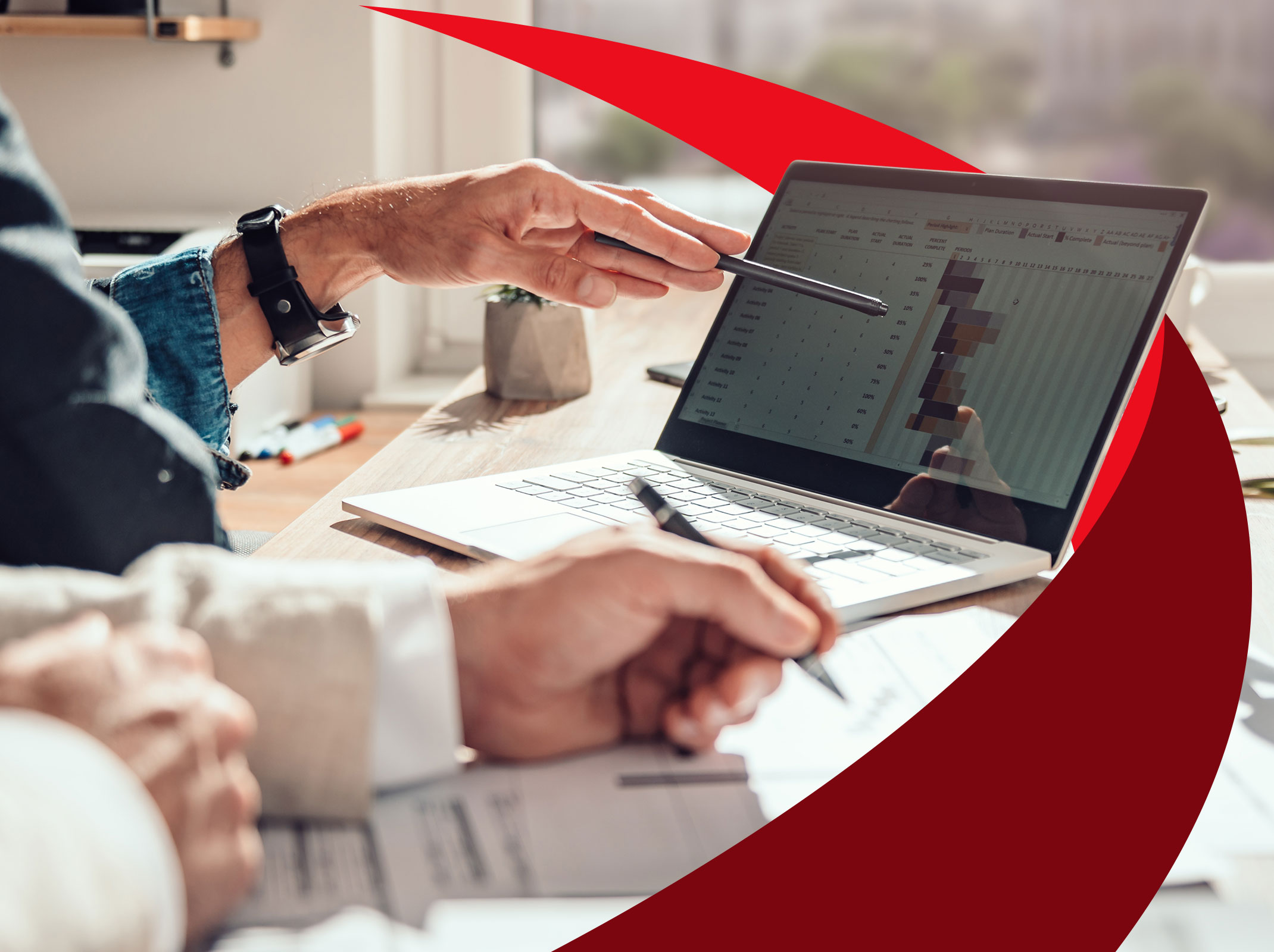 Two professionals sitting at a conference table with a laptop reviewing the project management action plan.
