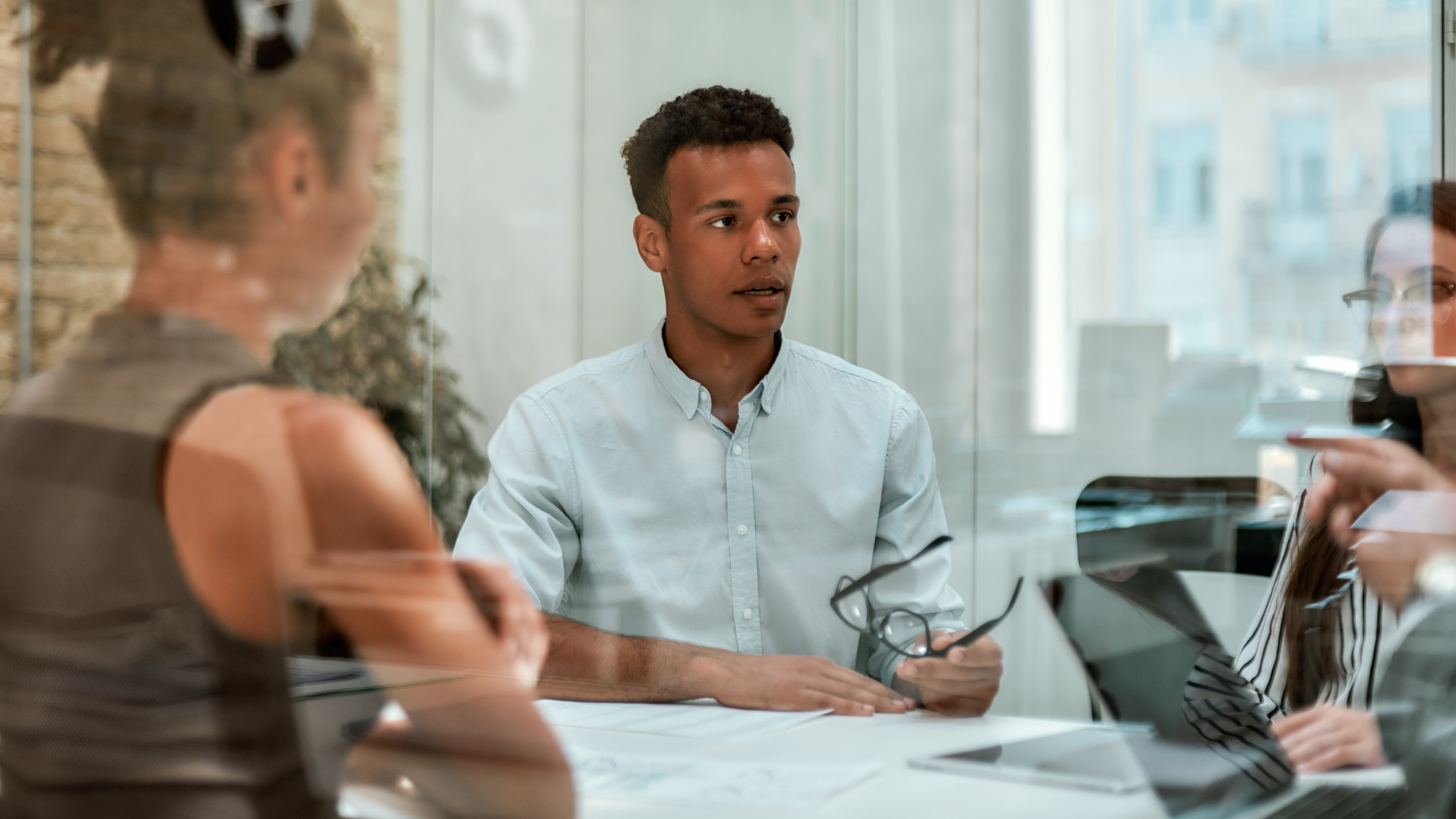 Young man speaking to a table of coworkers during a meeting